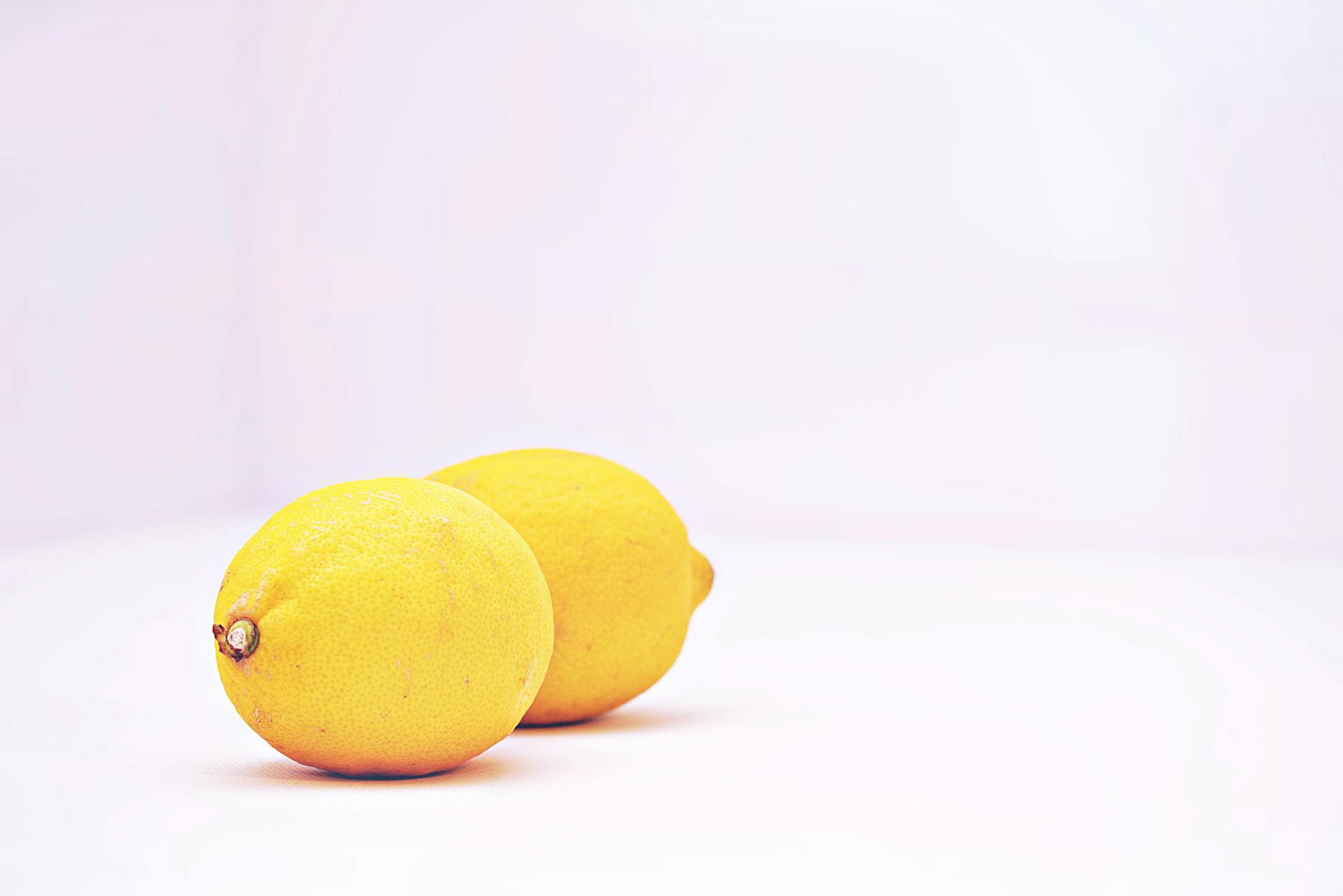 Two vibrant yellow lemons on a minimalist white background, symbolizing fresh sensation and reconnection