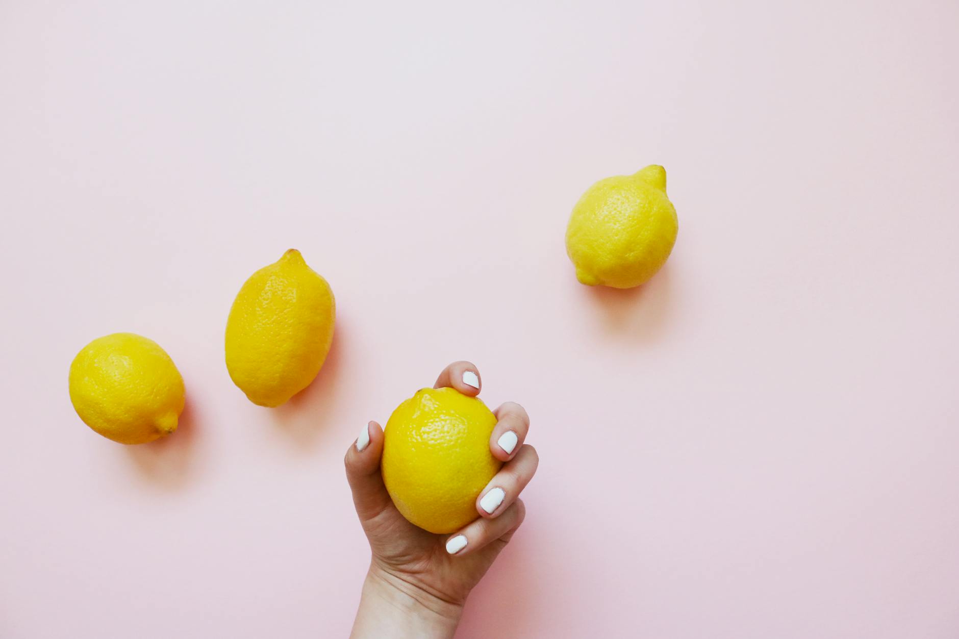 Hands holding lemons on a soft pink background, symbolizing fresh approaches to intimacy