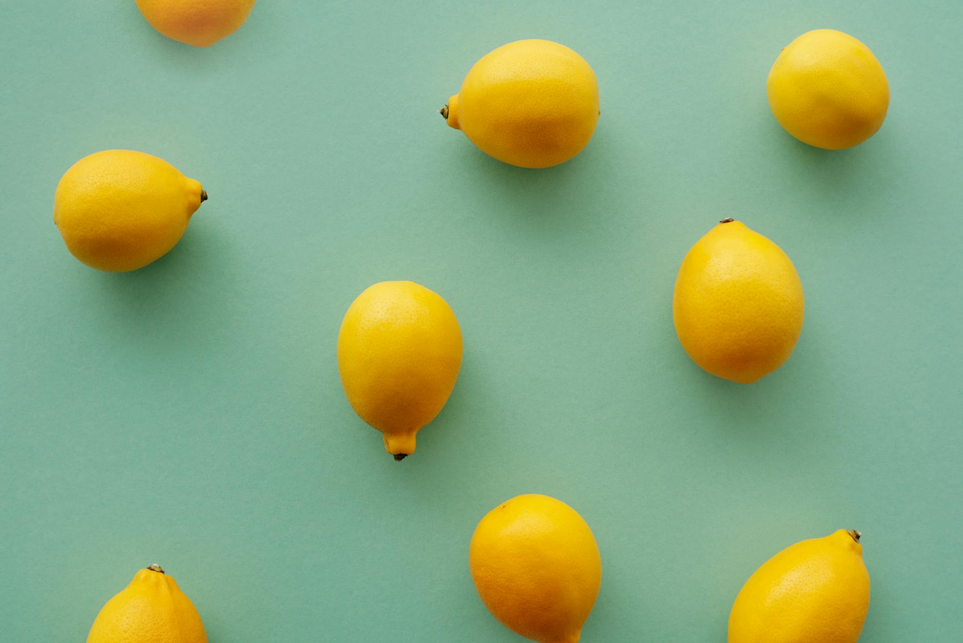 Bright yellow lemons arranged on a pastel green background, symbolizing fresh sensation and vitality.