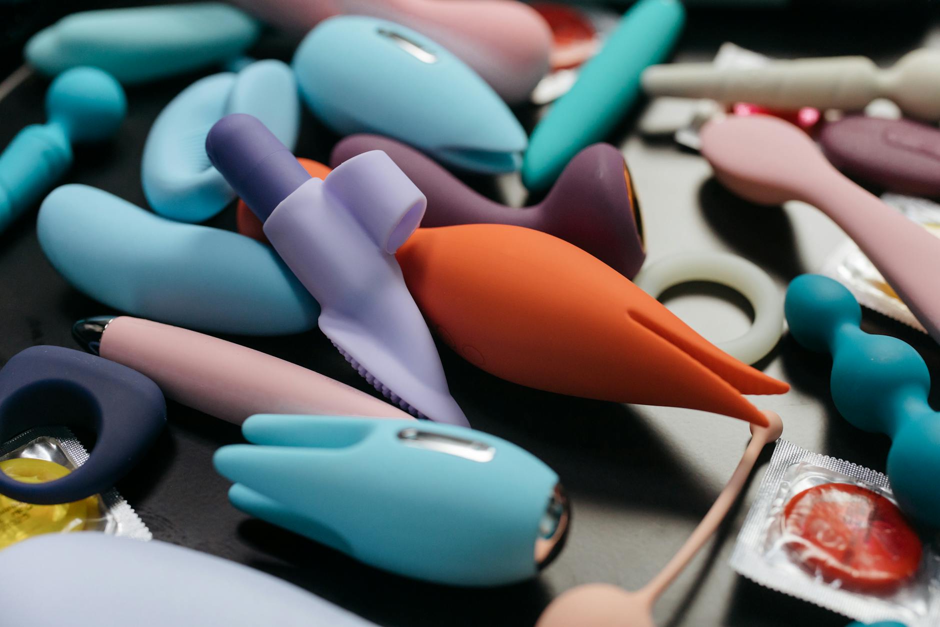 Hand holding a vibrant orange vibrator against a minimalist purple backdrop
