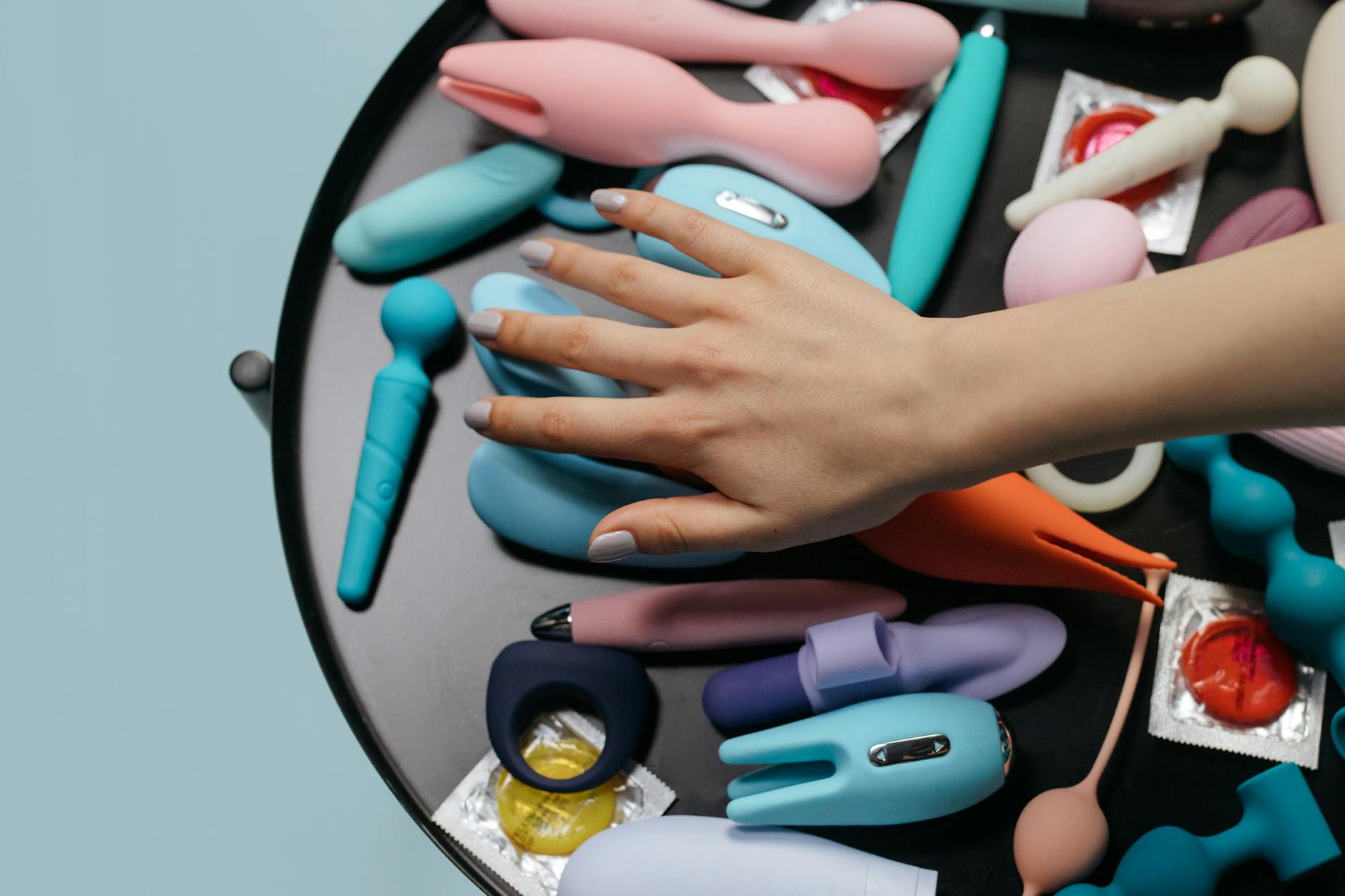 Hand holding an orange suction vibrator against a purple backdrop