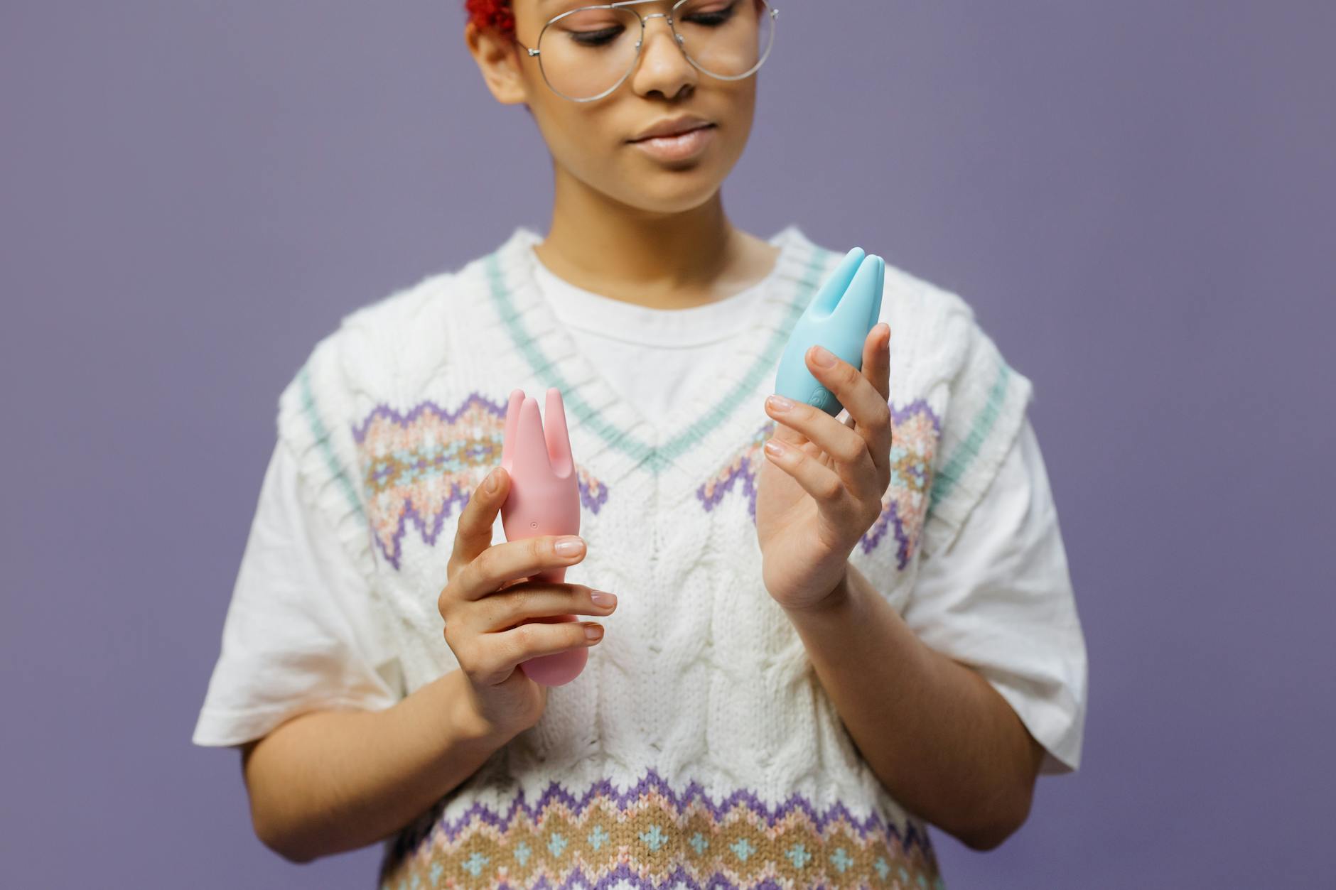 Mujer sosteniendo vibradores de colores azul y rosa en contemplación profunda